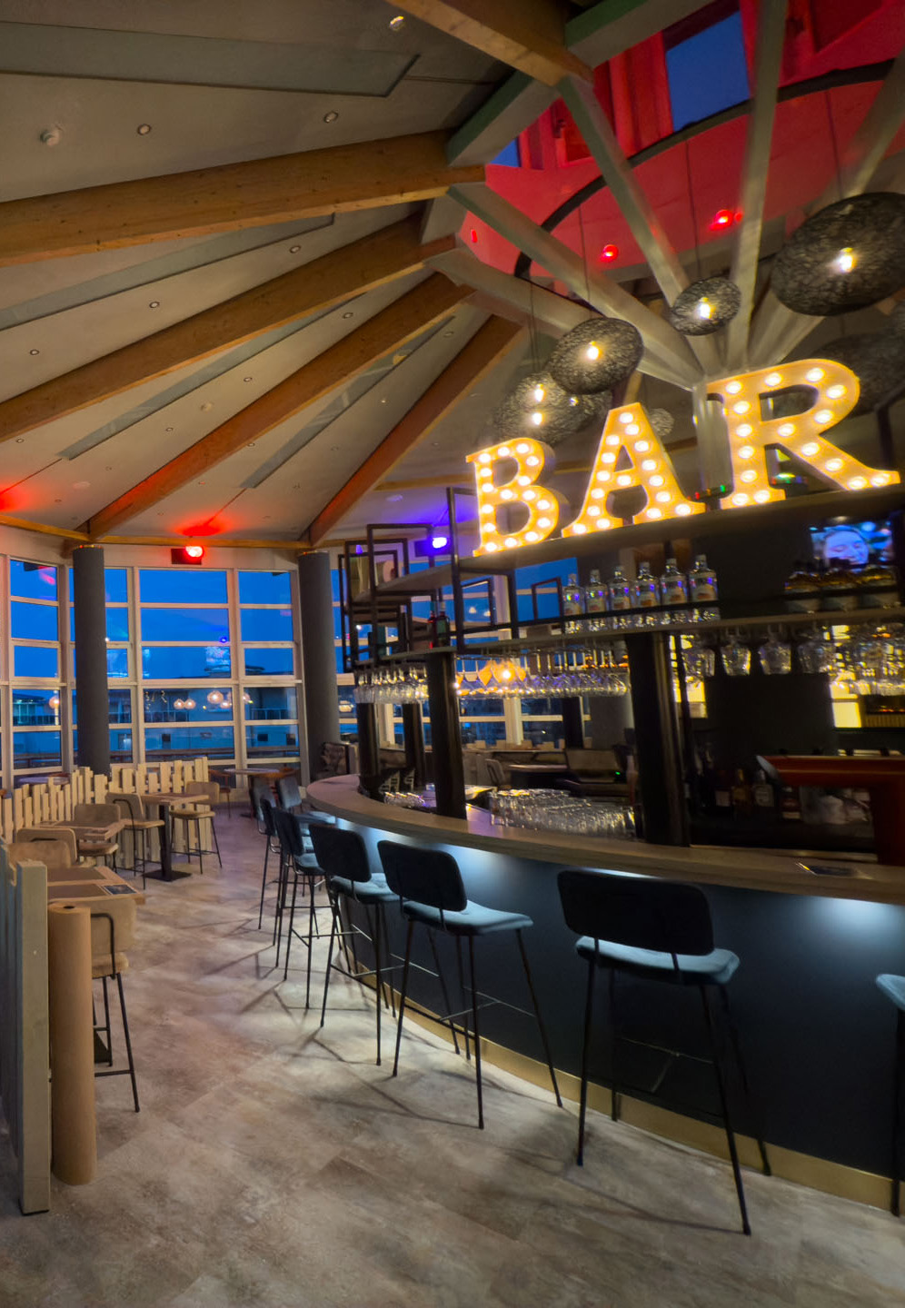 Geräumige Bar im modernen Stil mit großen Fenstern und leuchtendem "BAR"-Schild.