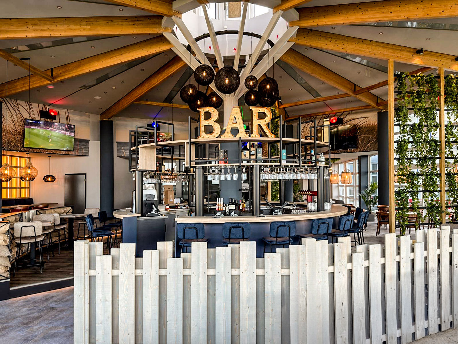 StormyBAR mit zentralem Tresen, holzverkleideter Decke und schickem Innendesign.