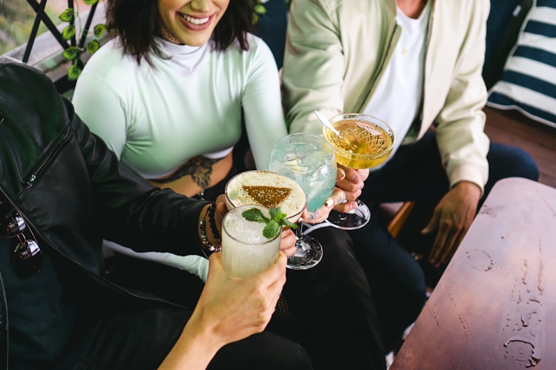 Drei Personen stoßen mit verschiedenen Cocktails an, lächelnd und entspannt in einer Lounge.