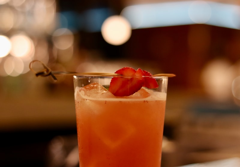 Ein Glas mit rotem Getränk, Eiswürfeln und Erdbeeren als Dekoration auf einem Cocktail.